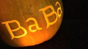 Een uitgeholde pompoen met de tekst 'BaBa' van binnenuit verlicht.
