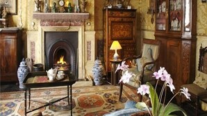 A traditional room with a fireplace, a table with teapots, a lamp, and a cabinet with glass doors.