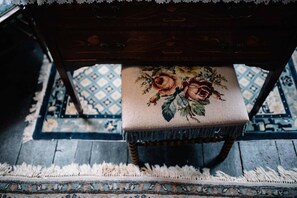Une chaise en bois avec un coussin à motifs floraux, une nappe en dentelle et un tapis à motifs.