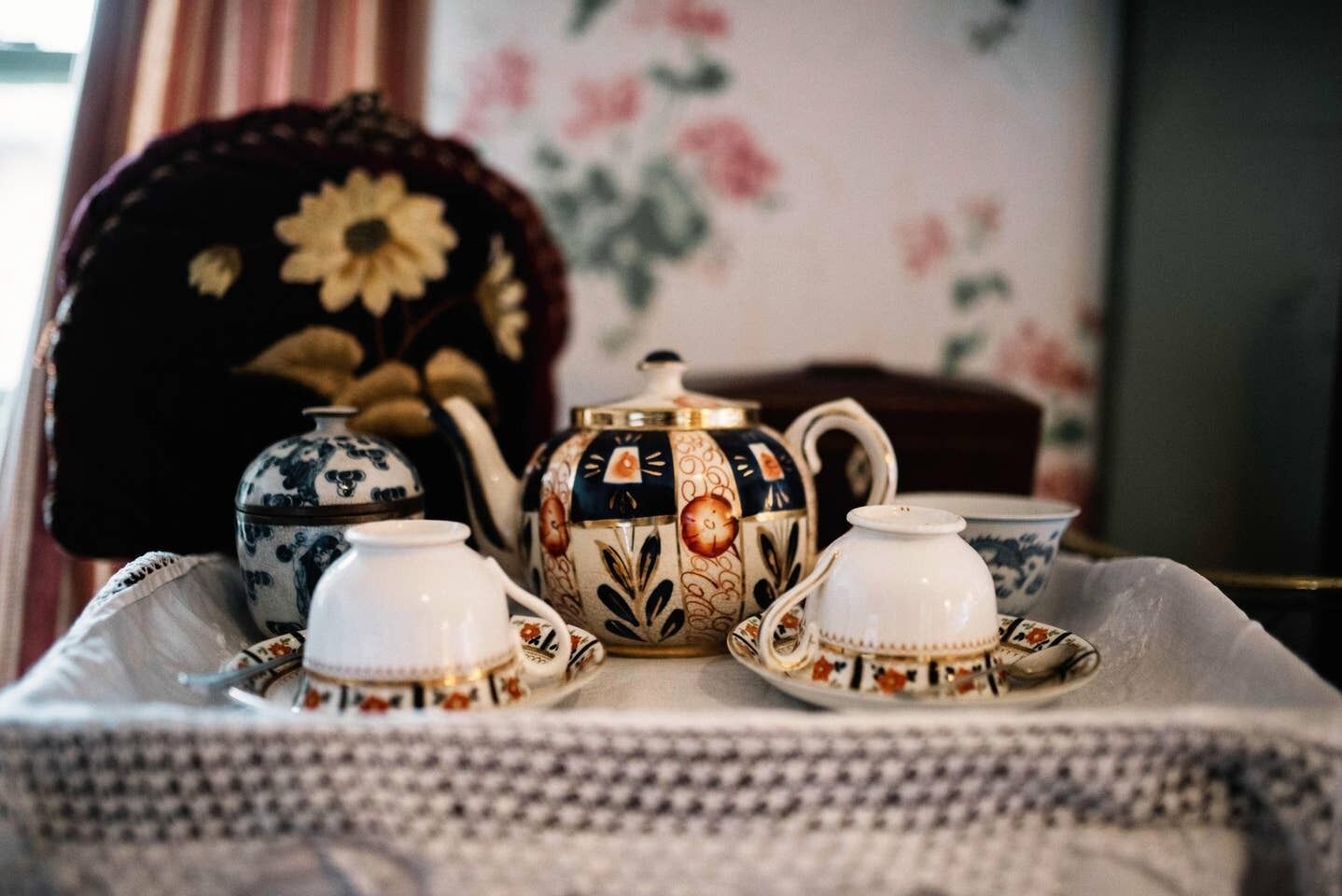 Una mesa servida con juego de té que incluye tetera, tazas y platillos.