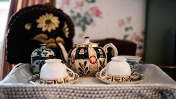 Una mesa servida con juego de té que incluye tetera, tazas y platillos.