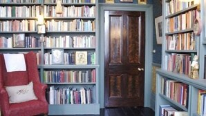 A room with a red armchair, a bookshelf filled with books, and a wooden door.