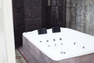 Un área de spa con un jacuzzi grande y rectangular y dos sillones de masaje negros.