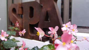A sign with the letters "SPA" in a rustic metal font, surrounded by pink flowers with yellow centers.