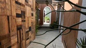 A narrow stone pathway leading to a building entrance with a wooden wall on one side. - La Casa del Atrio (Querétaro)