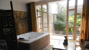 A bathroom with a large bathtub, a shower, and a toilet. There is a window with a view of greenery outside. - La Casa del Atrio (Querétaro)