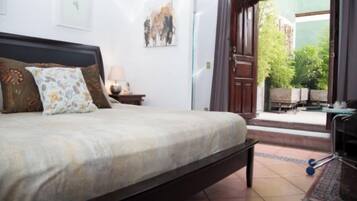A bedroom with a bed, a nightstand, a lamp, and a view of the outdoors.
