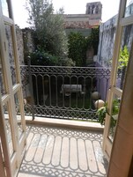 Una puerta abierta que da a un patio con un banco y plantas en macetas.