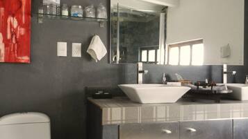 Un bagno moderno con uno specchio grande, un lavandino bianco e un water.