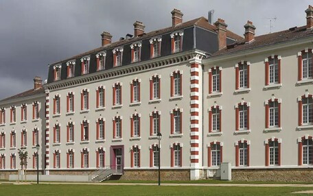 A large, historic building with a symmetrical facade, multiple windows, and a central staircase.