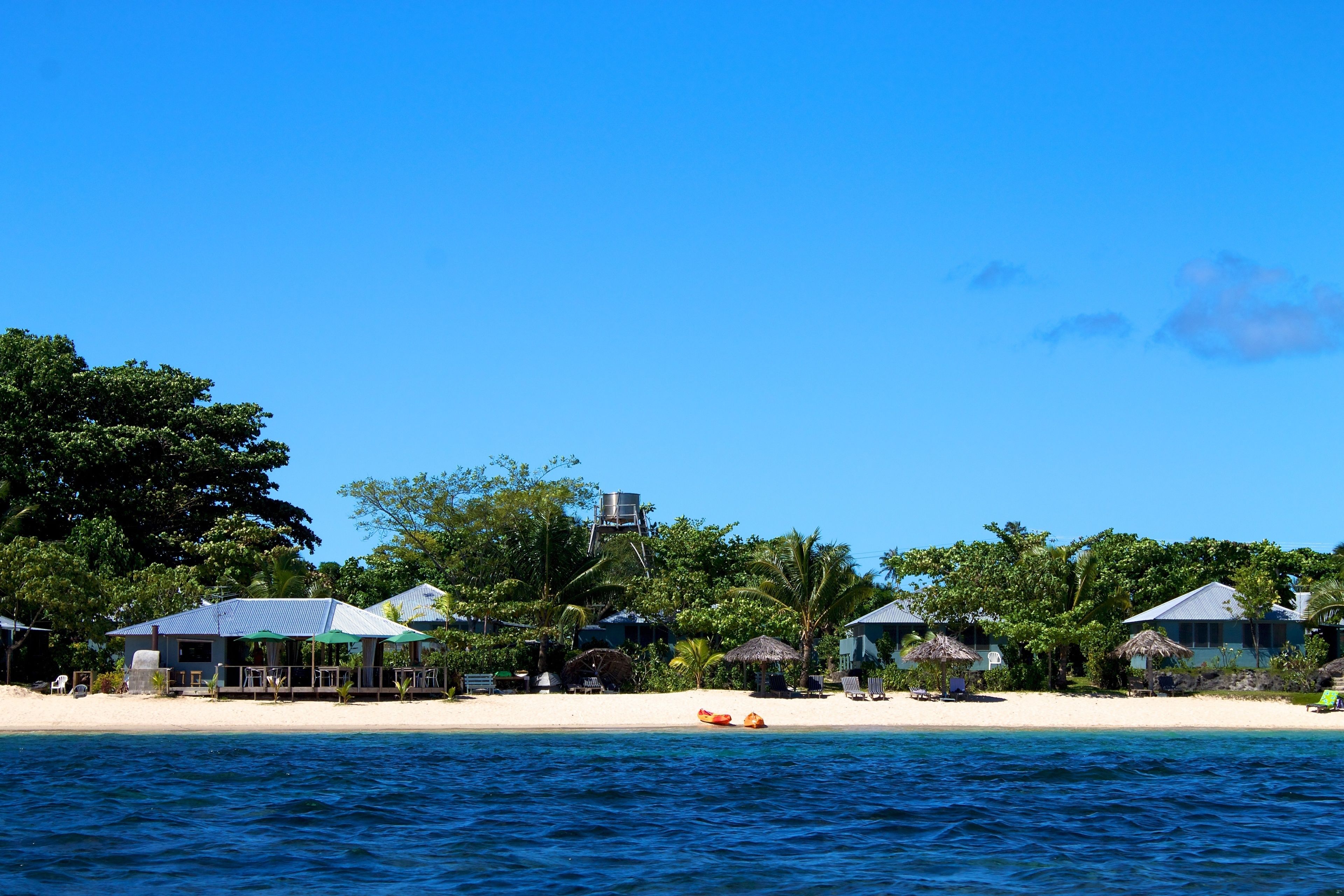 A beachside resort with overwater bungalows, a water tower, and a sandy beach.