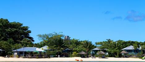 A beachside resort with overwater bungalows, a water tower, and a sandy beach.