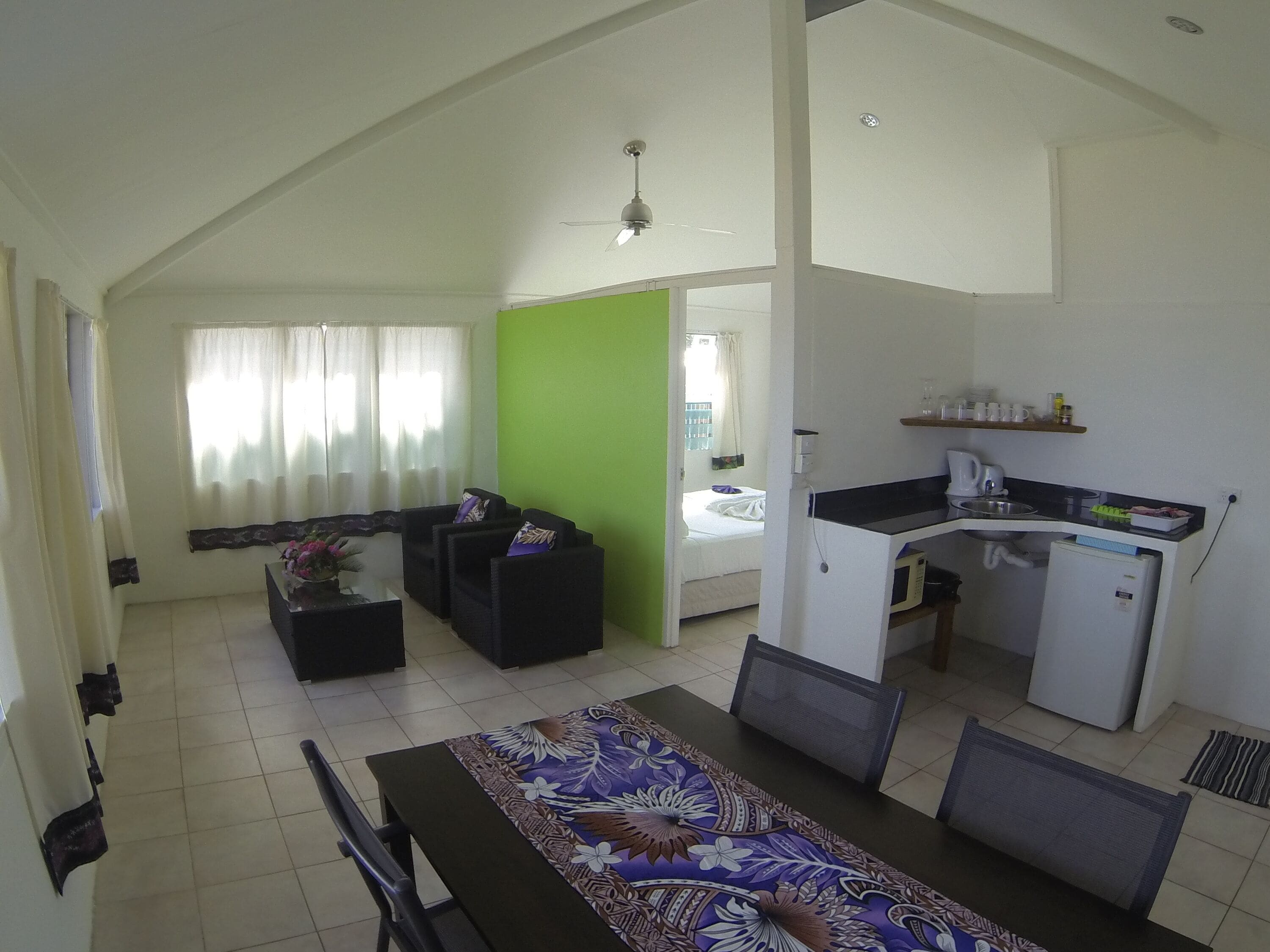 A compact living space with a dining area, kitchenette, and a bed.