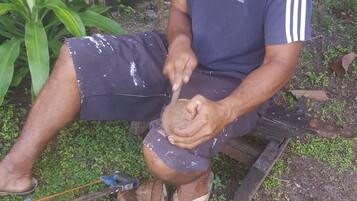 Una persona al aire libre cortando un coco con un cuchillo.
