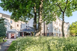 A multi-story building with a central courtyard, surrounded by lush greenery and a gazebo. - The Scholar (Edinburgh)