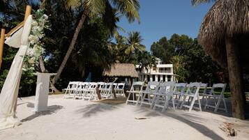 Decoração de casamento na praia com cadeiras e arco brancos.