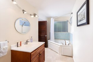 A bathroom with a sink, mirror, and bathtub.