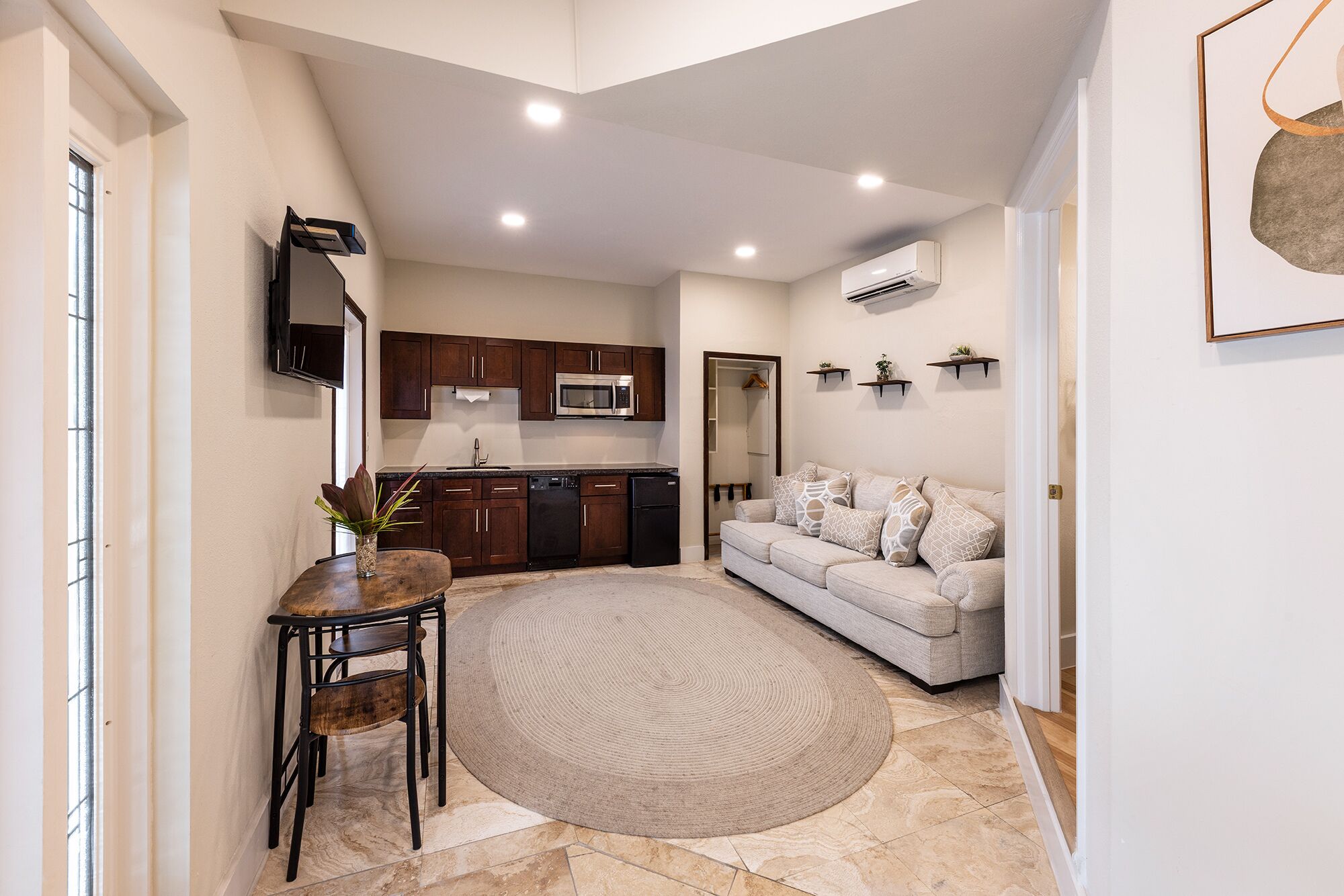 A compact living space with a kitchenette, a sofa, a dining table with chairs, and a decorative rug.