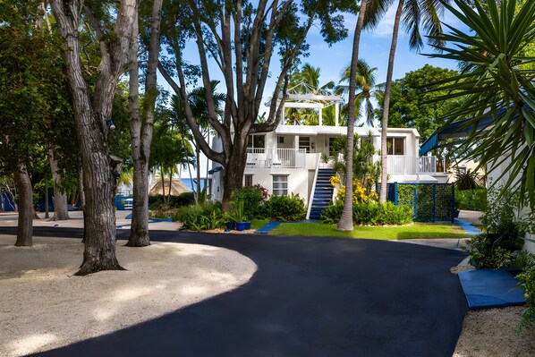 A two-story building with a balcony, surrounded by palm trees and a well-maintained garden.