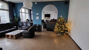 A modern lounge area with leather seating, a wooden coffee table, a decorated Christmas tree, and a view of the city through large windows.