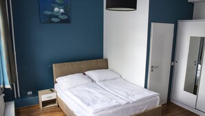 A bedroom with a bed, a nightstand, a wardrobe, and a painting on the wall.