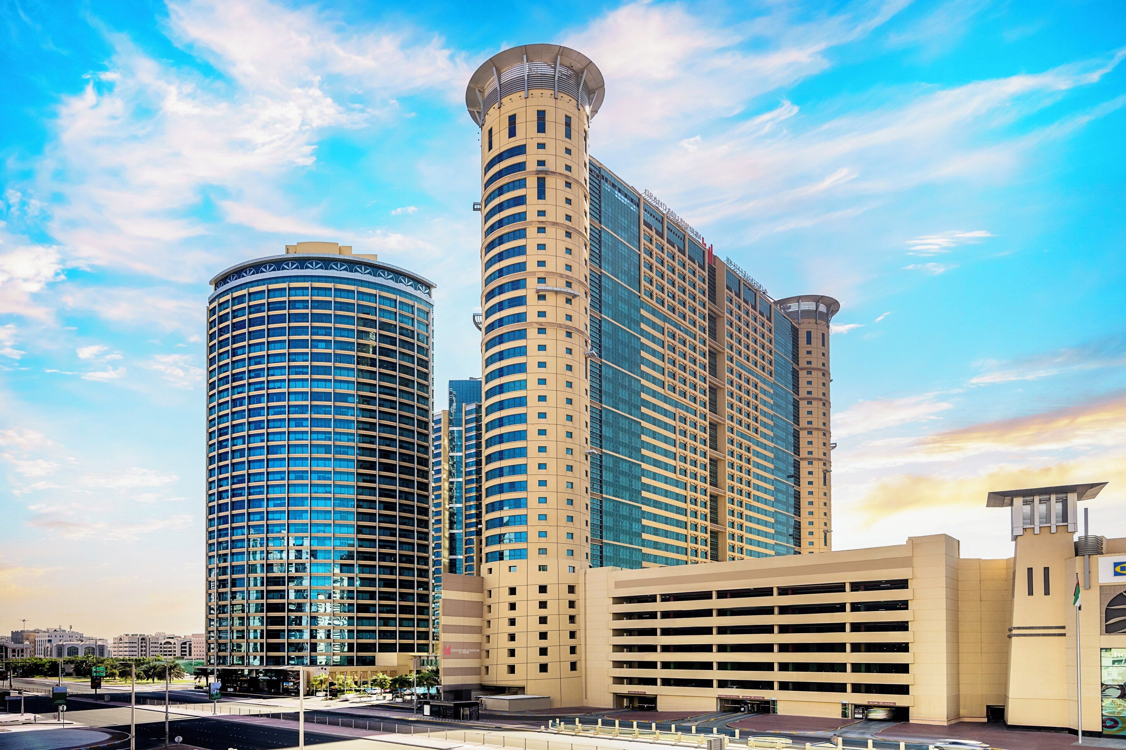 A modern hotel with two cylindrical towers, a parking garage, and a clear sky.