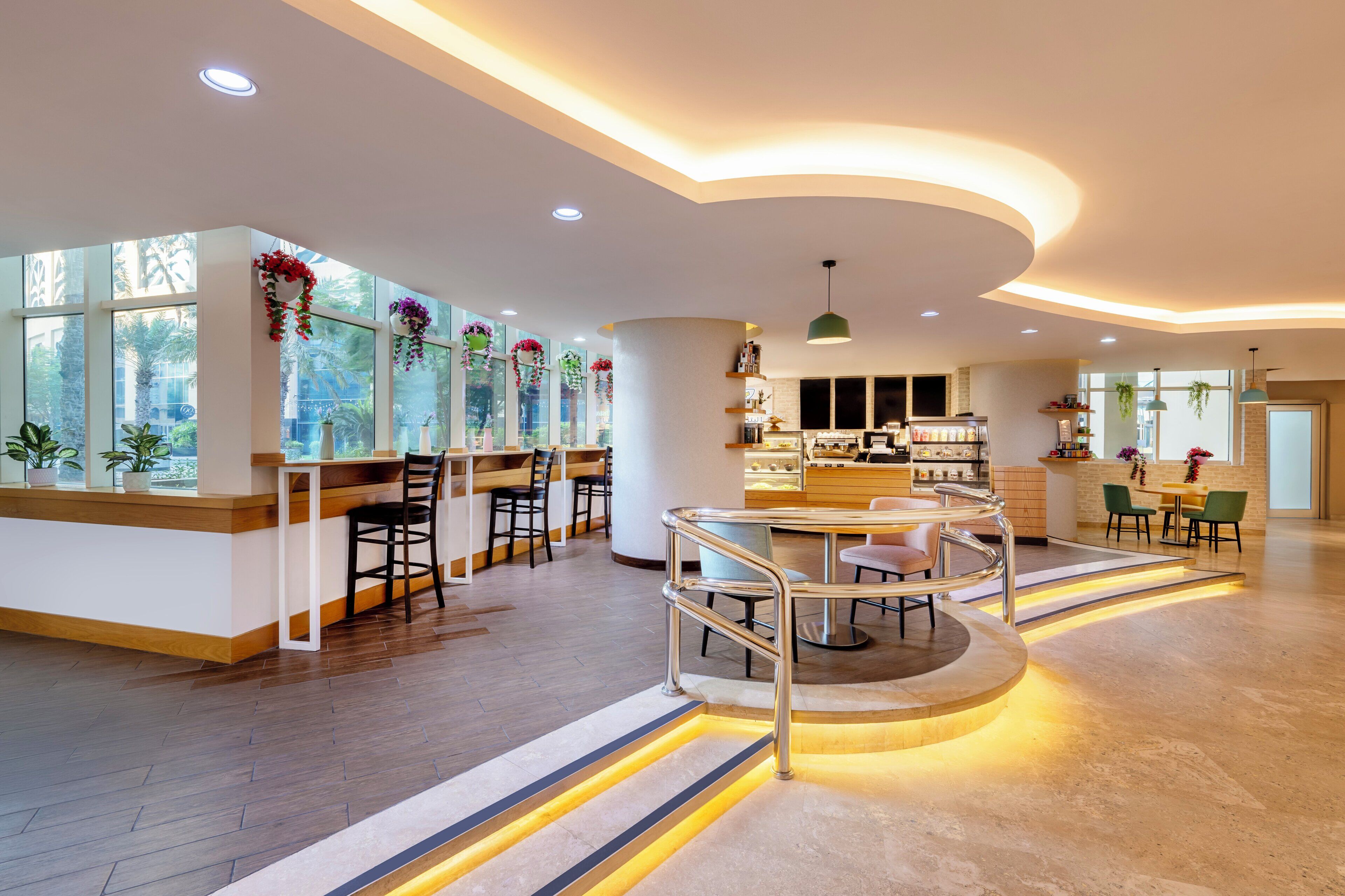 A modern interior with a central seating area, a bar, and large windows with plants.