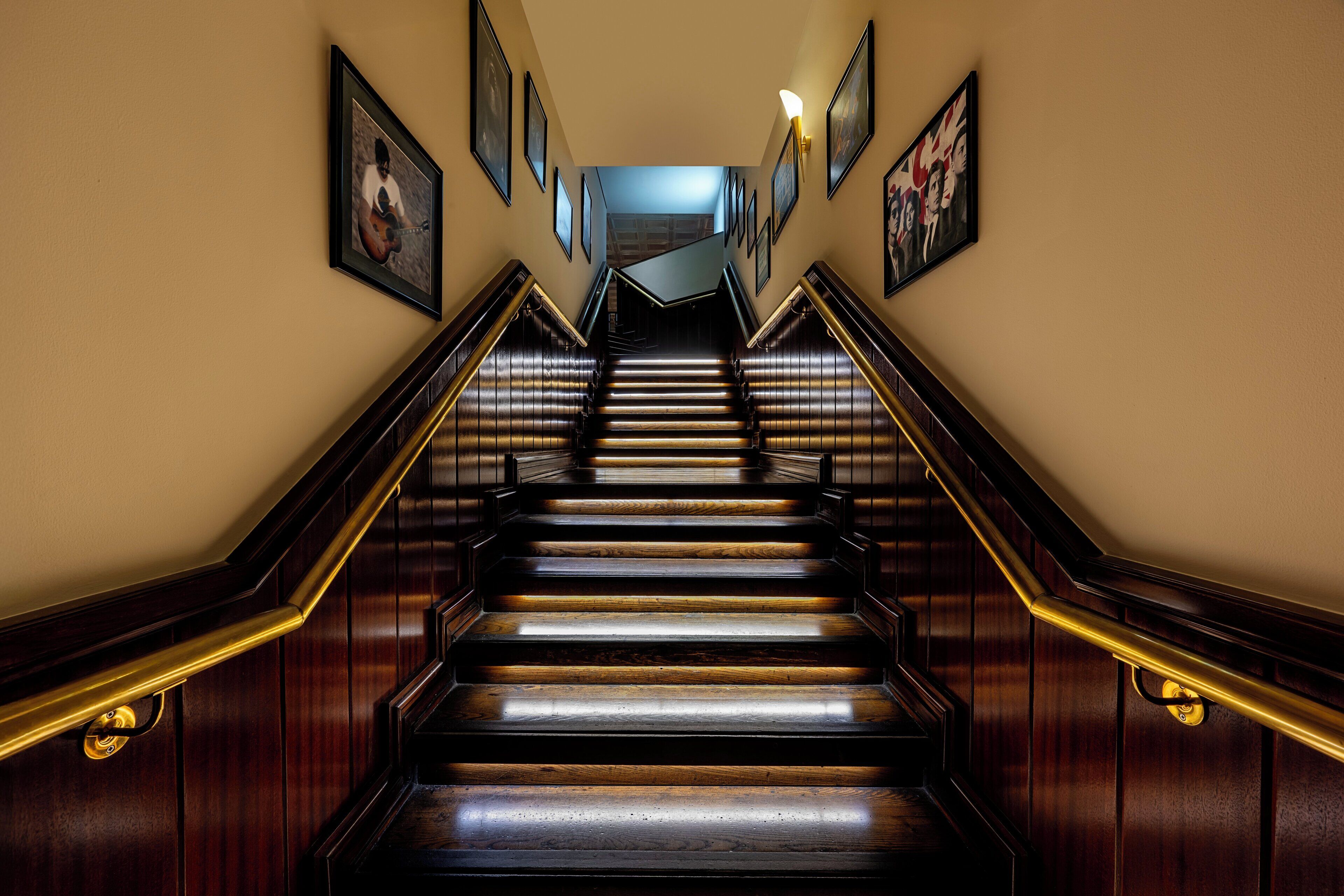 A grand staircase with wooden steps and brass railings, leading to a landing with a view of the upper floor.