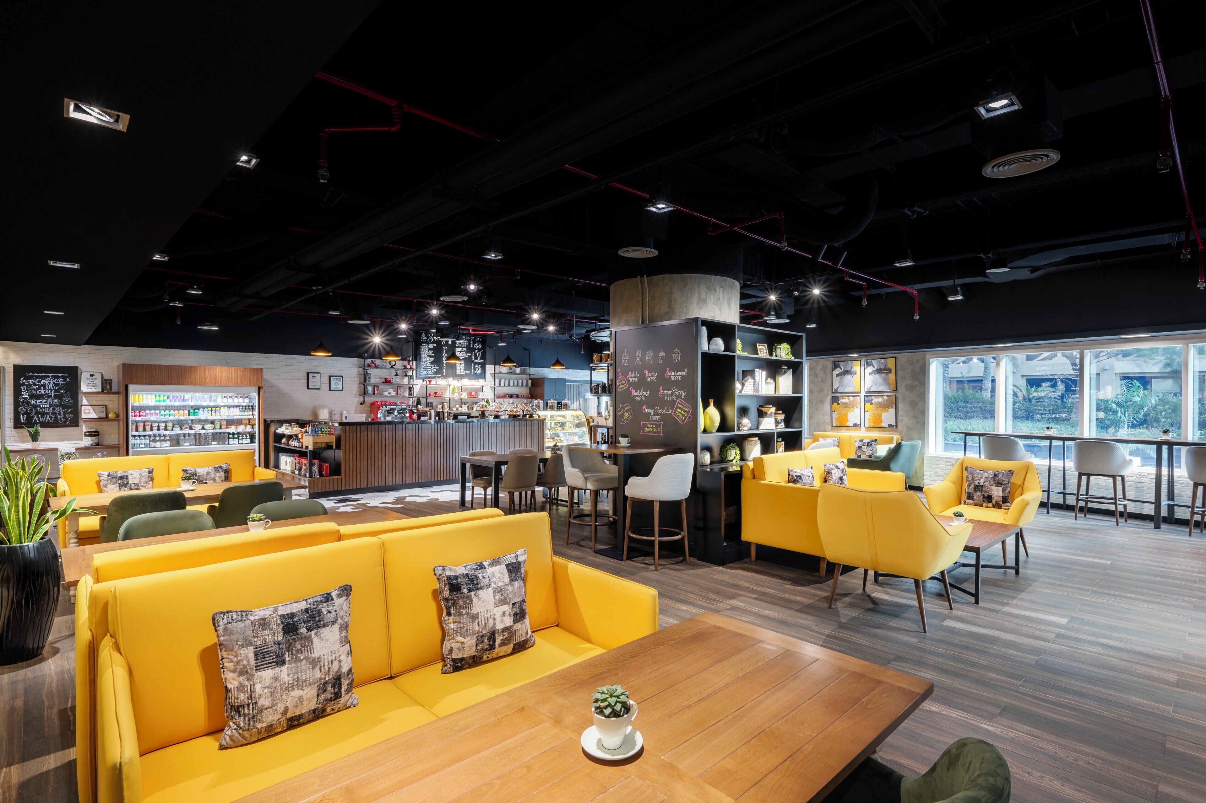 A modern cafe with yellow seating, a bar area, and large windows.