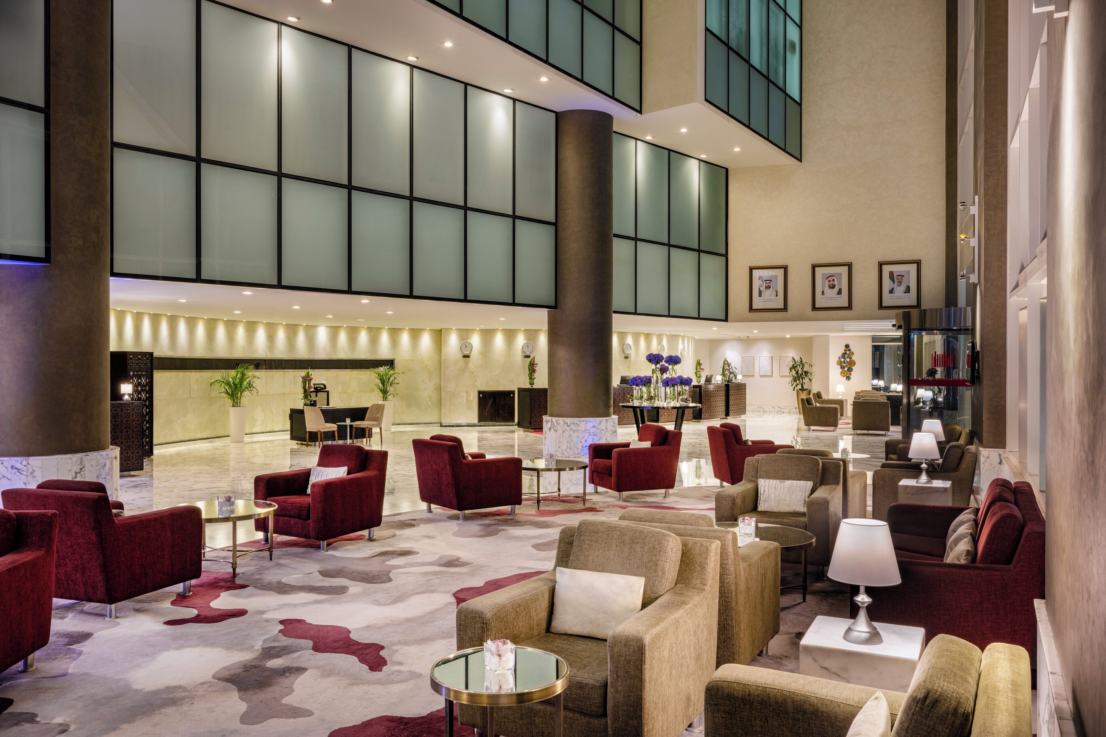 A spacious lobby with multiple seating areas, a reception desk, and a large windowed wall.