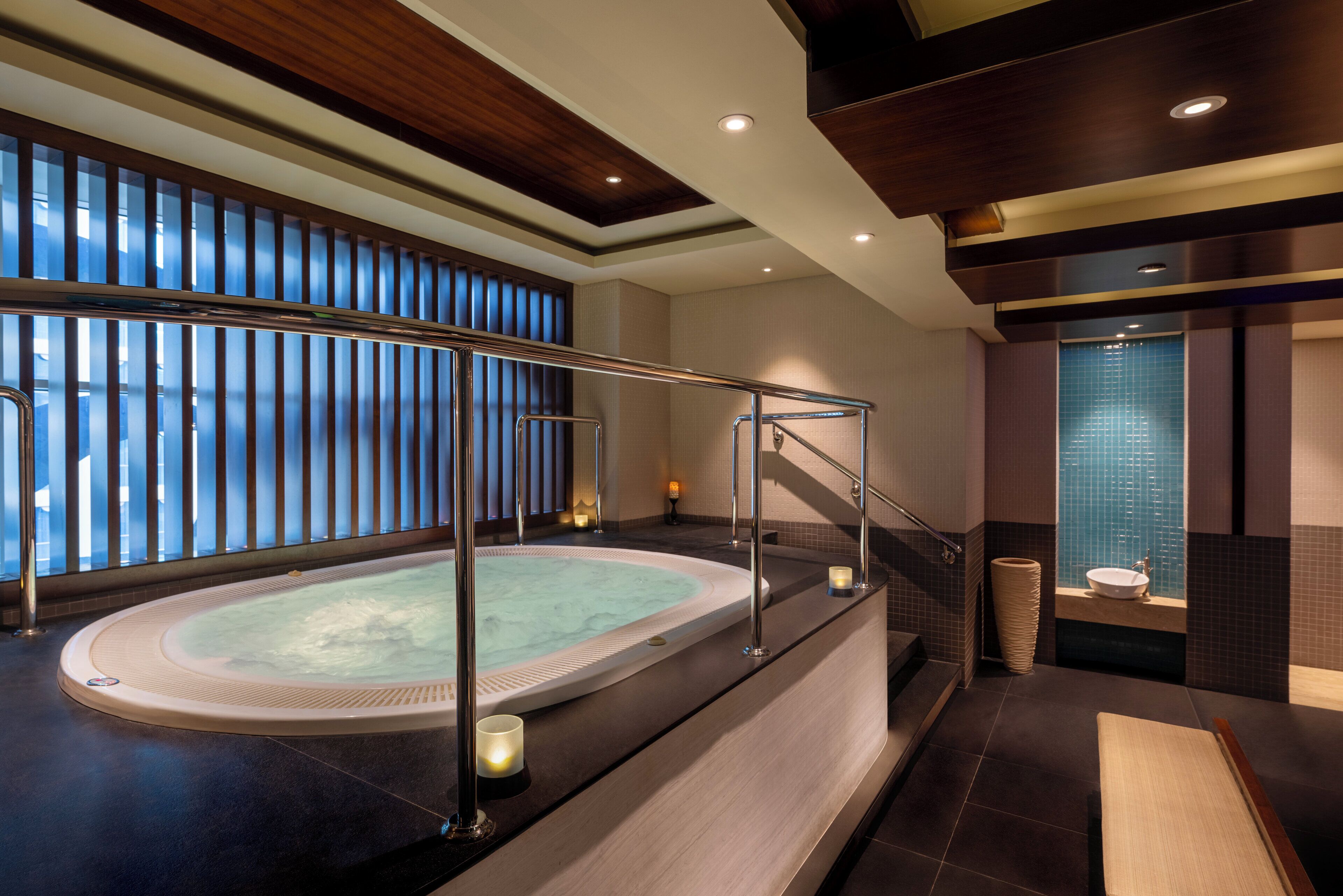 Een modern wellnessgedeelte met een jacuzzi, een houten plafond en een uitzicht door een raam.