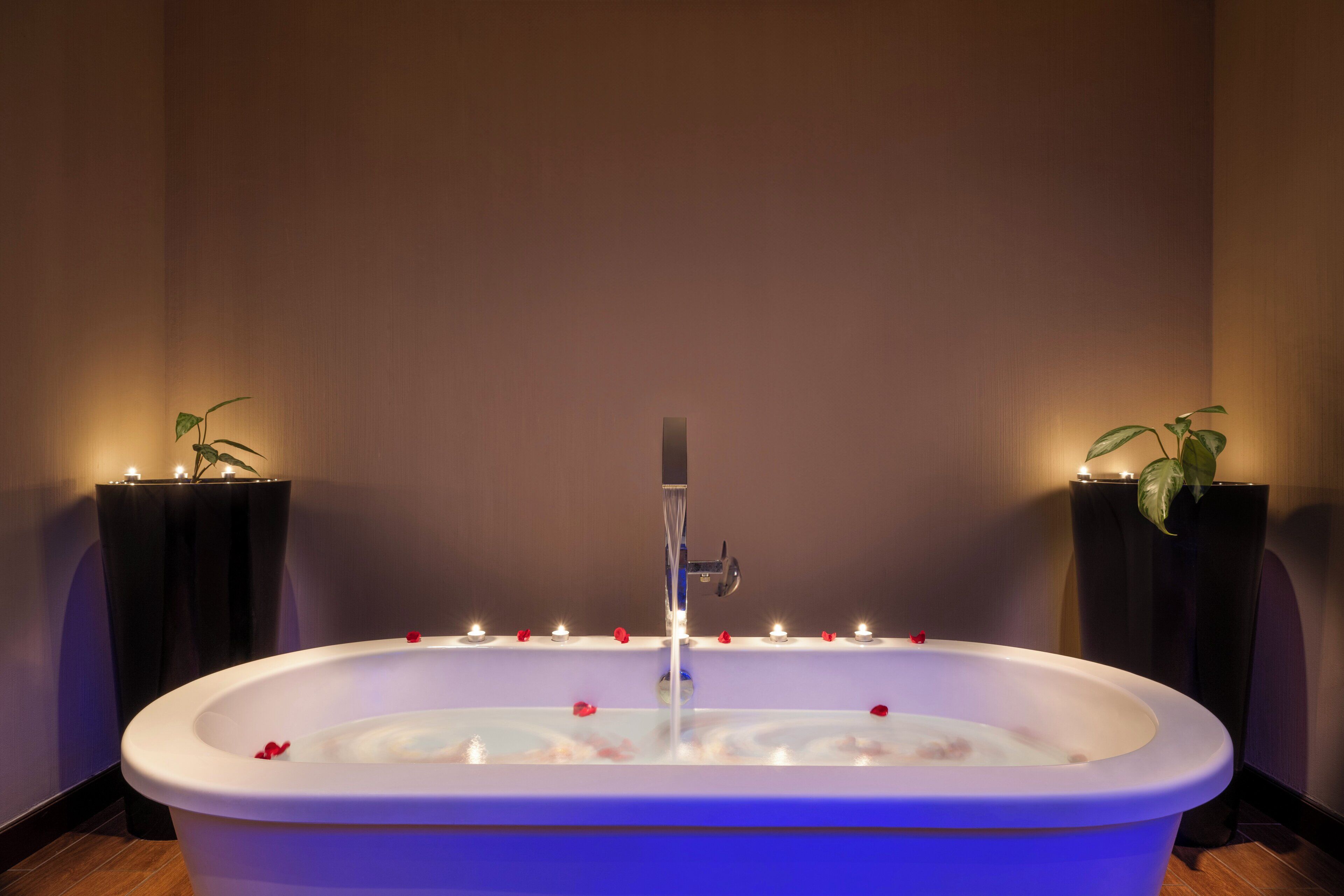 A bathtub with rose petals and candles.