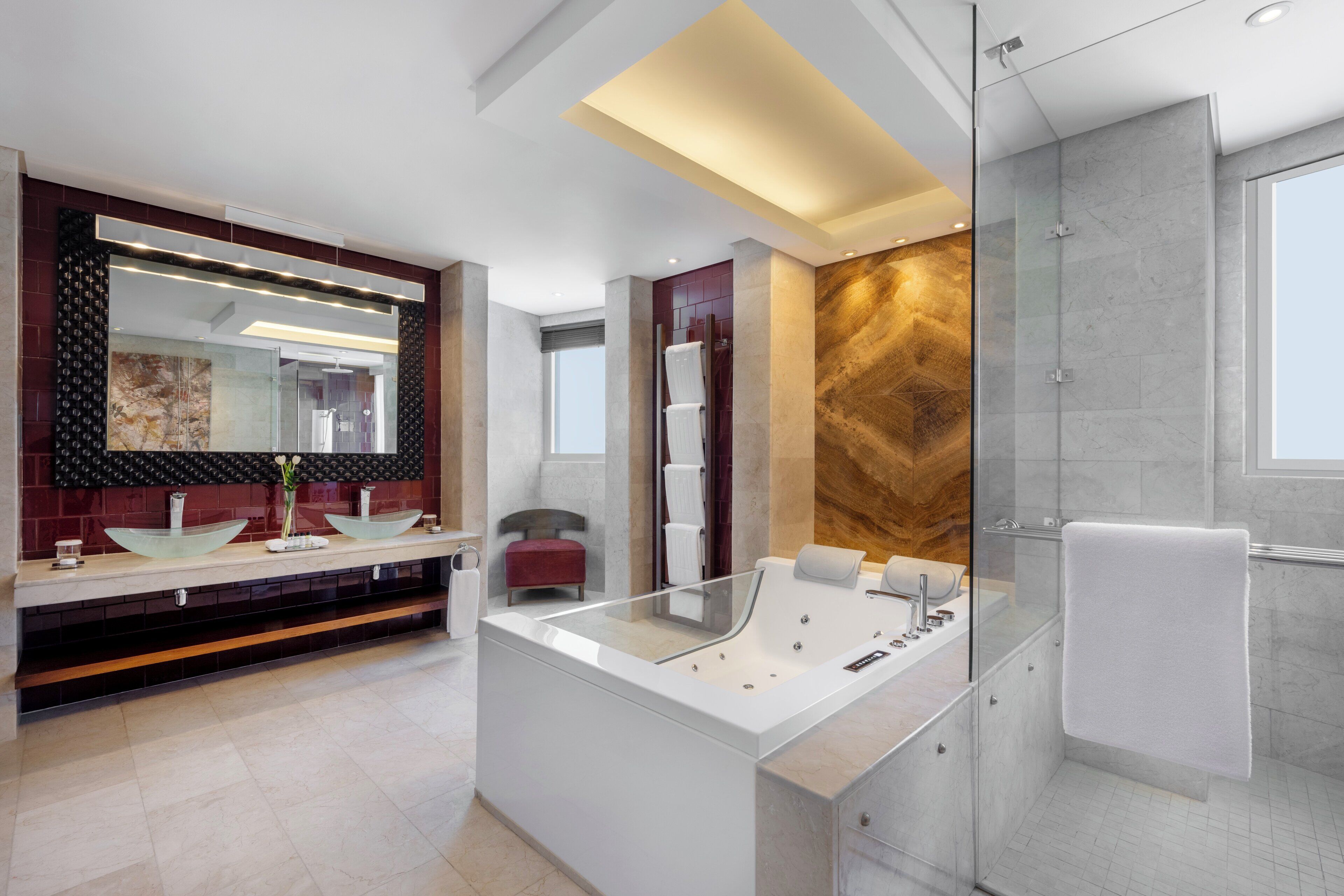 A modern bathroom with a glass-enclosed shower, a large mirror, and a central island with a bathtub.