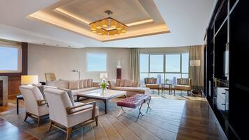 A spacious living room with a modern chandelier, large windows, and a view of the city skyline.