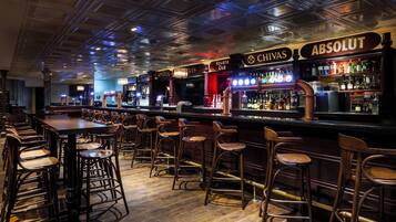 A bar area with stools and a long counter, featuring brands like Chivas and Absolut.
