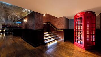 Un intérieur moderne avec un plancher en bois, un escalier et une cabine téléphonique rouge.