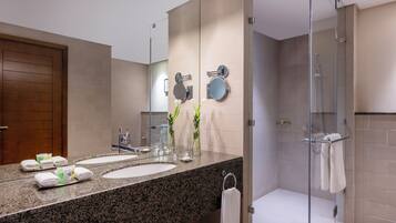 Une salle de bain moderne avec deux lavabos, un grand miroir et une douche à parois de verre.
