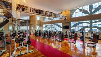 A spacious gym with various exercise equipment, large windows, and a red carpet.