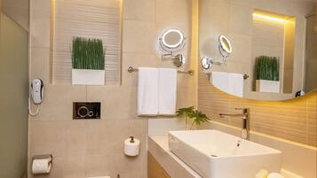 Un baño moderno con un espejo grande, un lavamanos blanco y un inodoro.