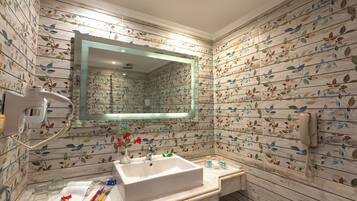 Un baño con un espejo grande, un lavamanos, un teléfono y un inodoro.