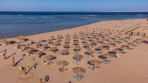 Vista aérea de una playa con numerosos sombrillas y sillas de playa dispuestas en filas.