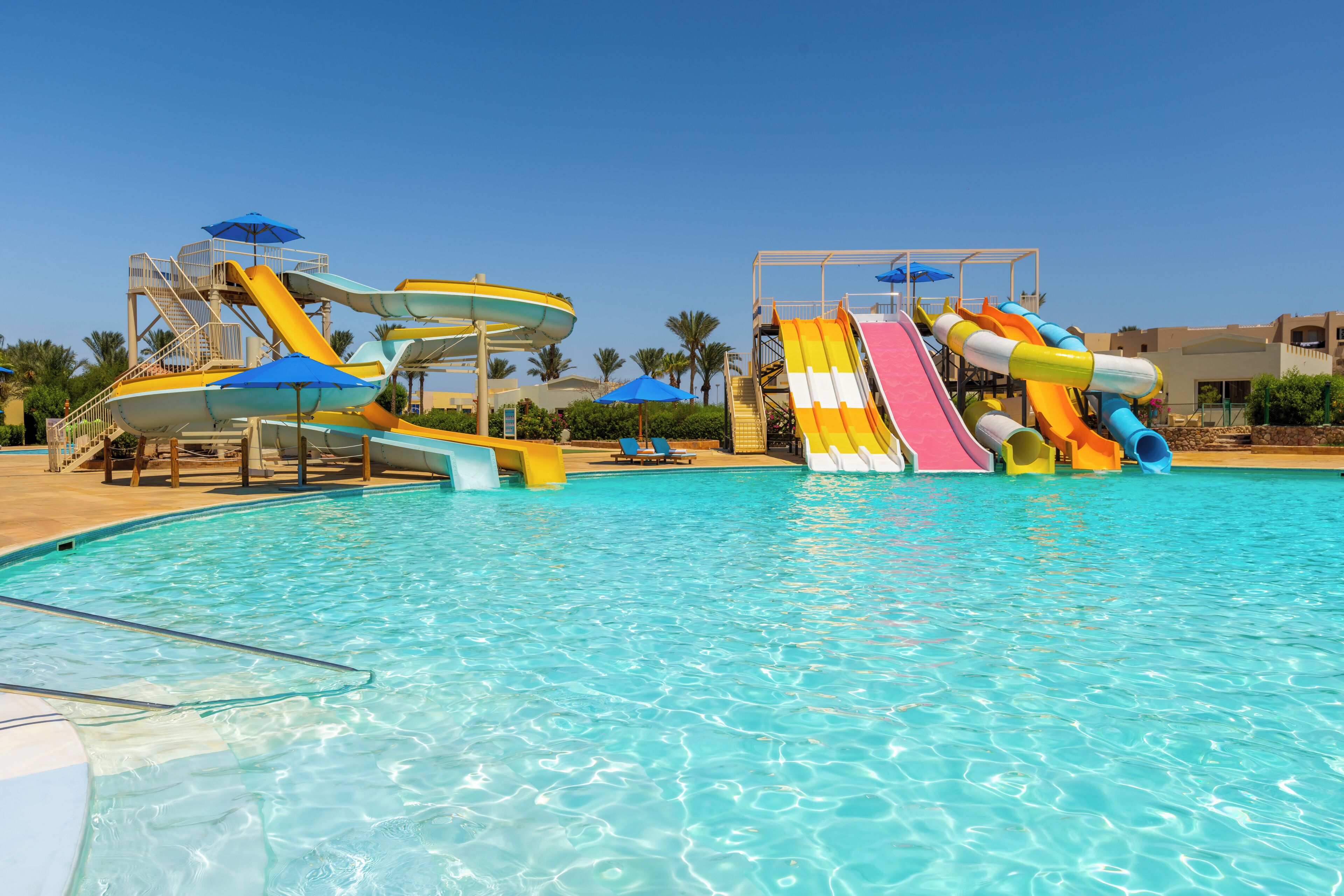 A swimming pool with multiple water slides and umbrellas.