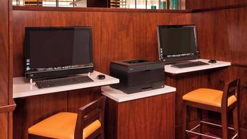 Two desks with laptops and printers, each with an orange chair.