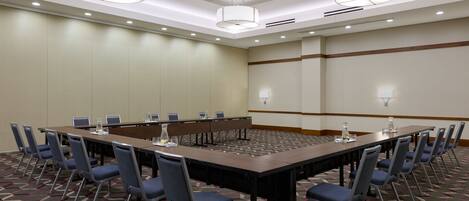 A conference room with a long table, chairs, and overhead lighting.