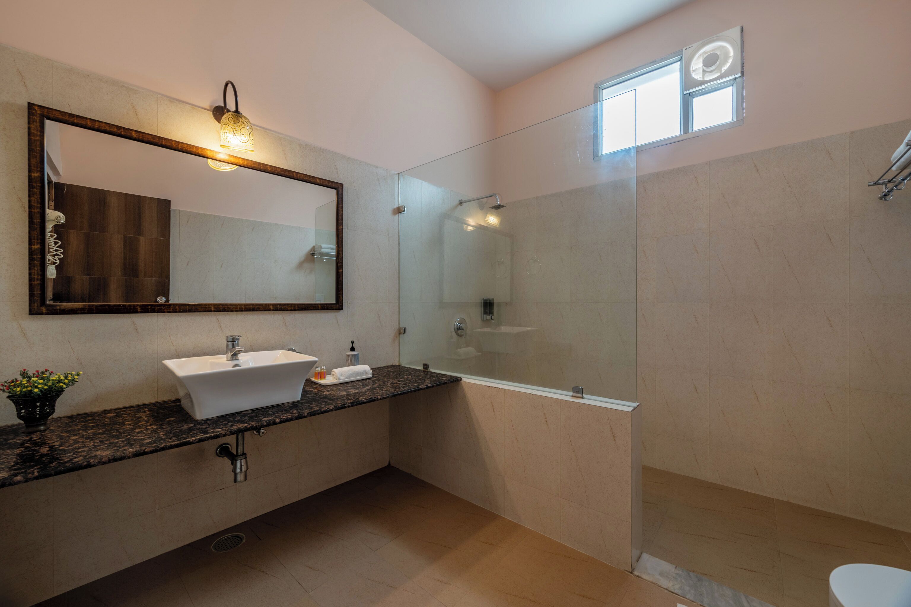 A modern bathroom with a large mirror, a sink, a shower, and a toilet.