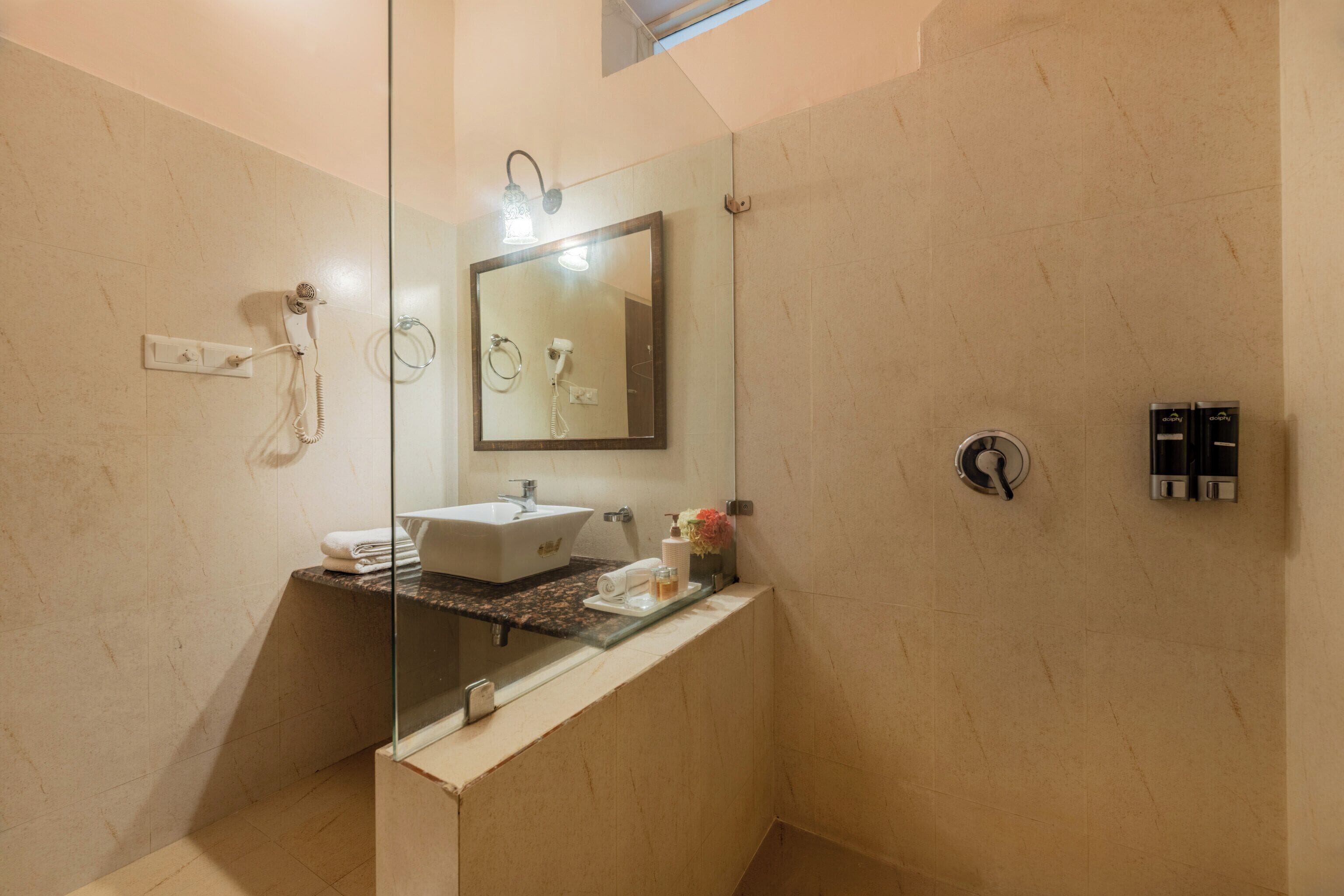A modern bathroom with a glass-enclosed shower, a sink with a marble countertop, a large mirror, and a towel rack.