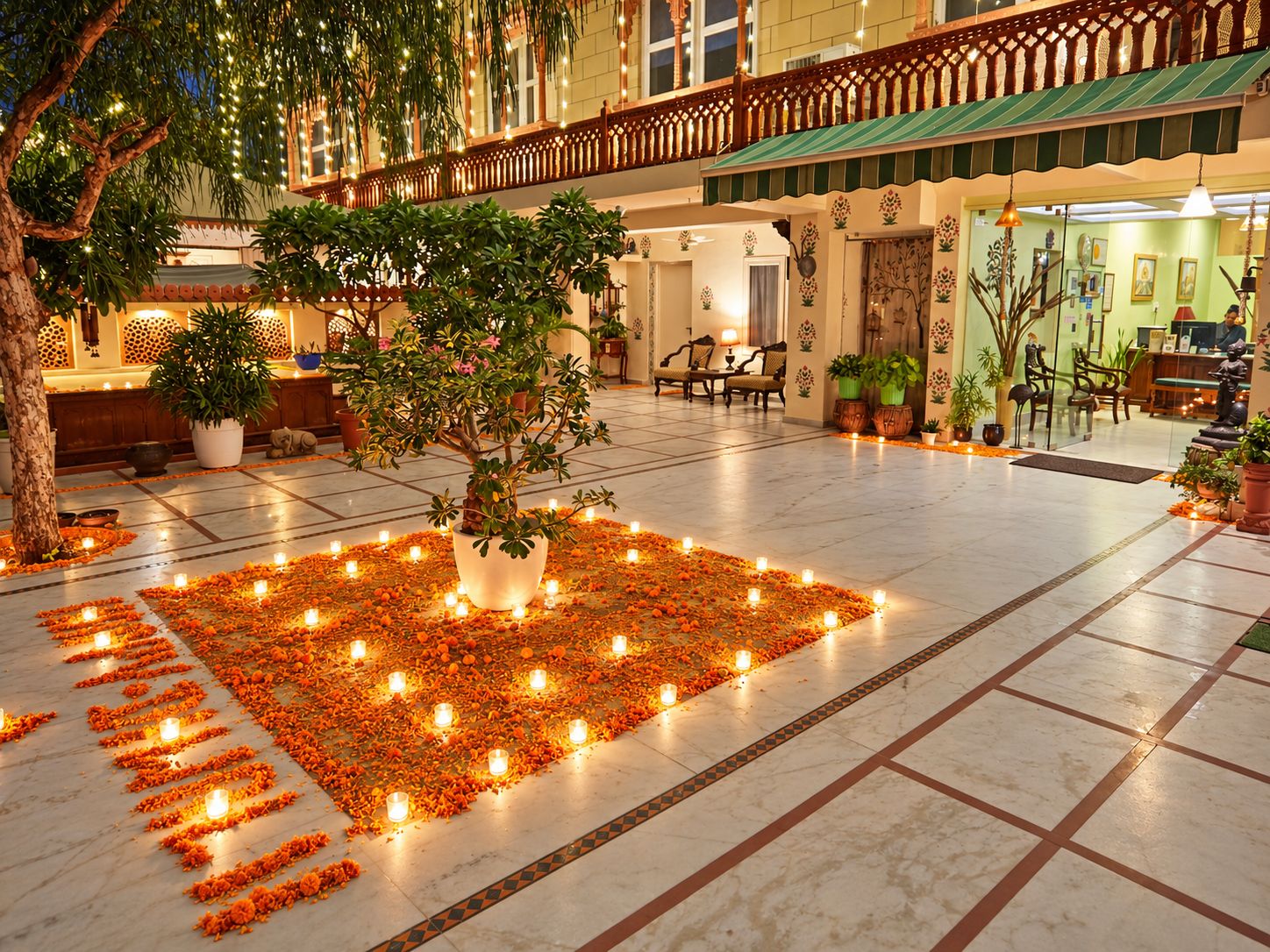Un vestíbulo de hotel con un patio central que cuenta con un árbol, plantas en macetas y una decoración floral con velas.
