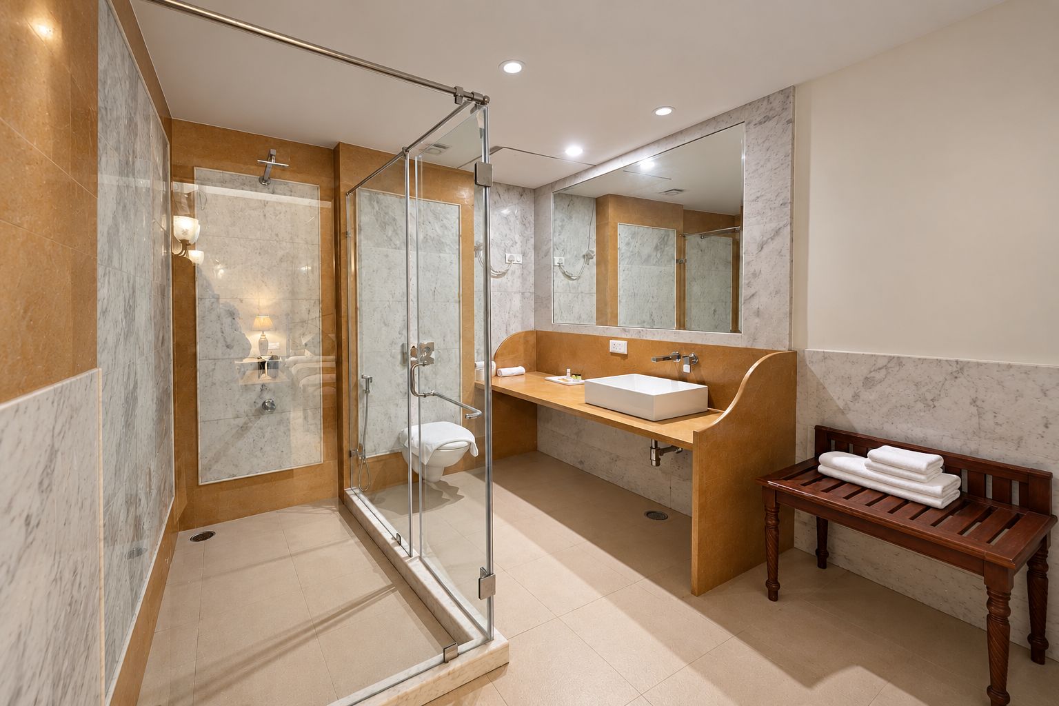 Un baño moderno con ducha envuelta en vidrio, suelo de mármol, banco de madera con toallas y un espejo grande.