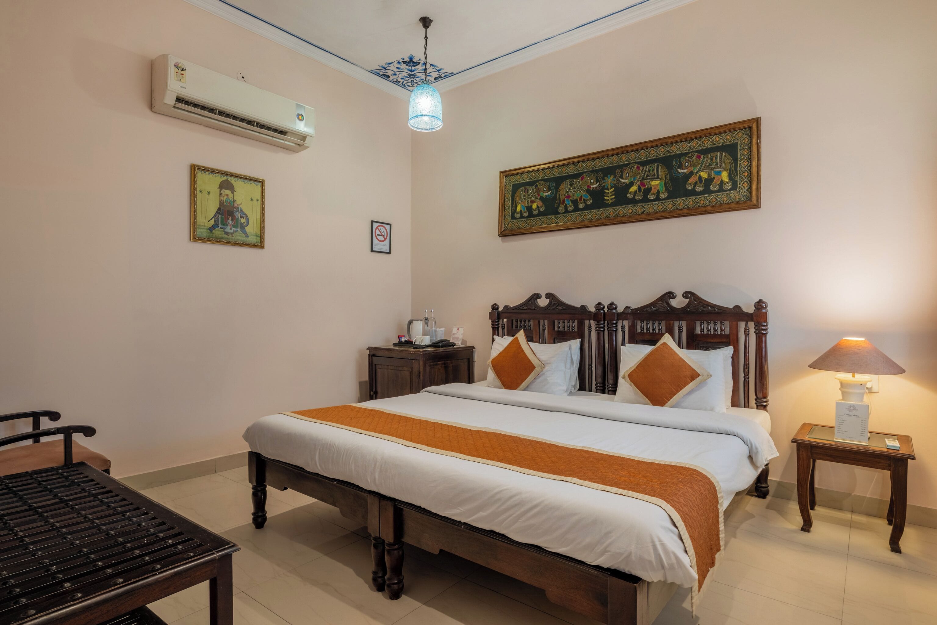 A neatly arranged bedroom with a bed, bedside table, lamp, and a small table with a chair.