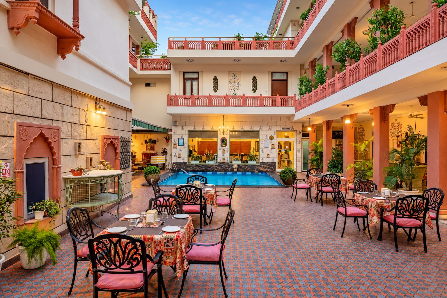 Un patio con piscina, zona de comedor con mesas y sillas, y un restaurante.